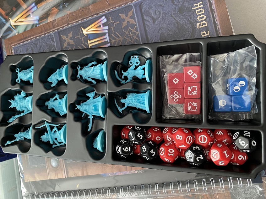 Miniature figures and dice in a black plastic box.